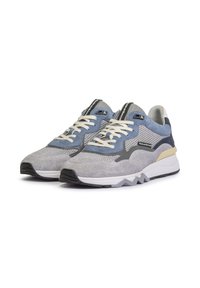 Sportliche Sneakers mit einem Obermaterial aus grauem und blauem Mesh, weißen Schnürsenkeln und einer stabilen Sohle in Schwarz und Beige, mit einem Zickzack-Profil.
