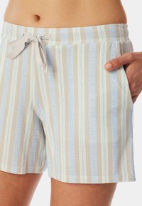 Randiga shorts i ljusbeige och blått, med ett mjukt tyg, ett elastiskt midjeband med snöre och sidofickor.