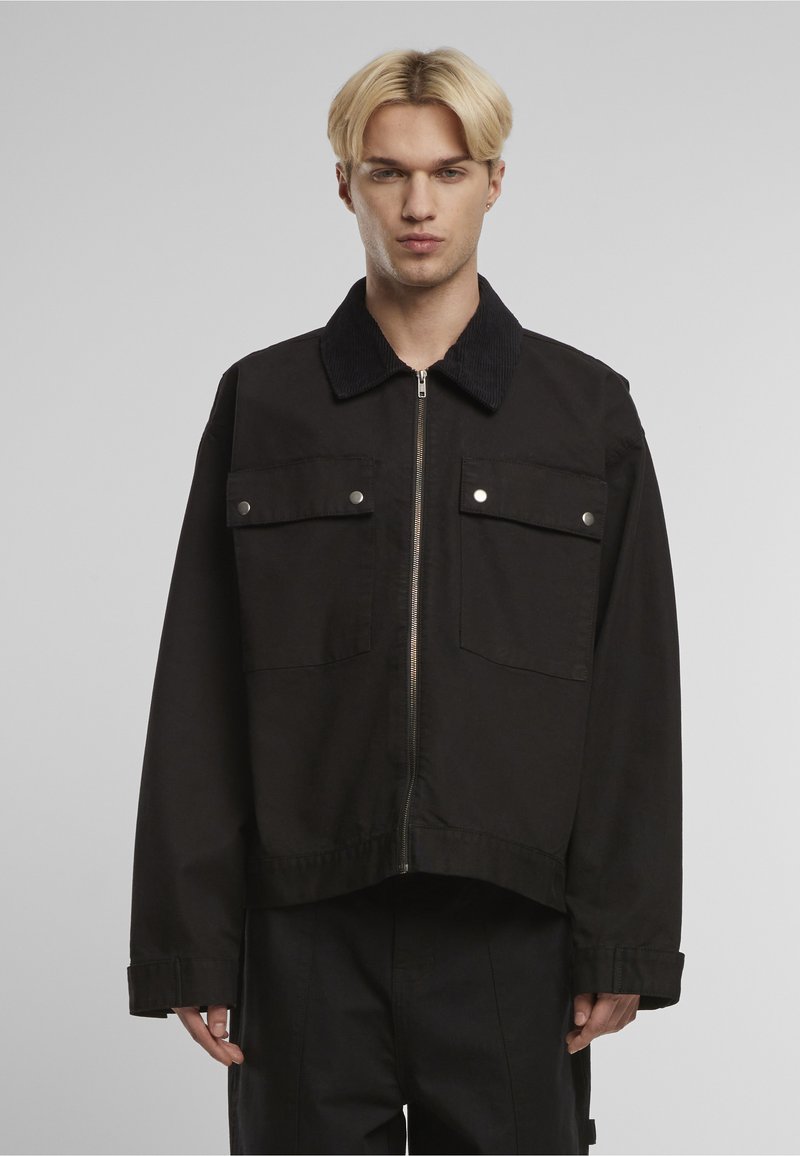 Czarna krótka kurtka z kordurowym kołnierzem, dwoma przednimi kieszeniami i srebrnymi okuciami. Posiada zamek błyskawiczny i gładką fakturę.