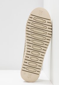 Suela de calzado de goma beige, con un patrón de agarre texturizado que presenta estrías horizontales y un logo en relieve, talla 37.
