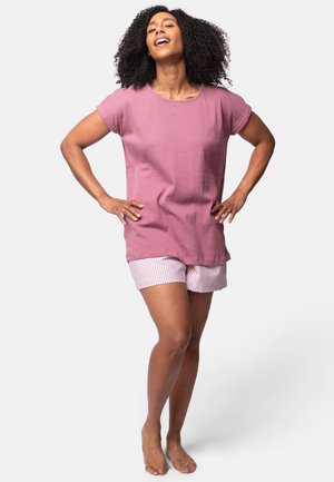 T-shirt oversized a righe rosa abbinato a pantaloni corti a strisce rosa e bianchi. Il tessuto appare morbido, con una vestibilità rilassata e maniche corte.