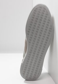 Szare zamszowe sneakersy z teksturowaną gumową podeszwą, płaskim krojem kostki i minimalistycznymi akcentami. Podeszwa ma wzorzystą powierzchnię zapewniającą stabilność.