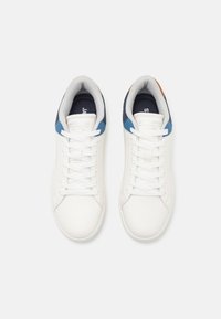 White sneakers with smooth leather material, round toes, and flat laces. Accents include a navy and blue heel and tan logo detail.