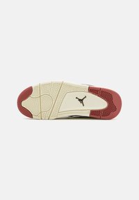 Suela de zapato con una base blanca y un patrón texturizado, acentos de goma roja y un logotipo negro. Diseñada para proporcionar tracción y soporte.