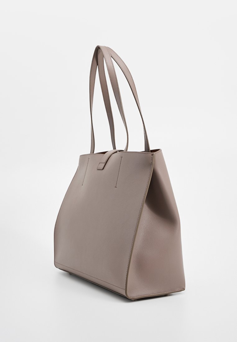 Graue Leder-Totetasche mit verjüngten Seiten, zwei langen Tragegriffen und einem minimalistischen Design. Glatte Textur ohne sichtbare Hardware oder Akzente.