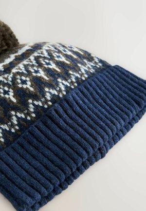 Knitted beanie with a dark blue ribbed cuff. The body features a geometric pattern in brown, white, and blue, topped with a brown pom-pom.
