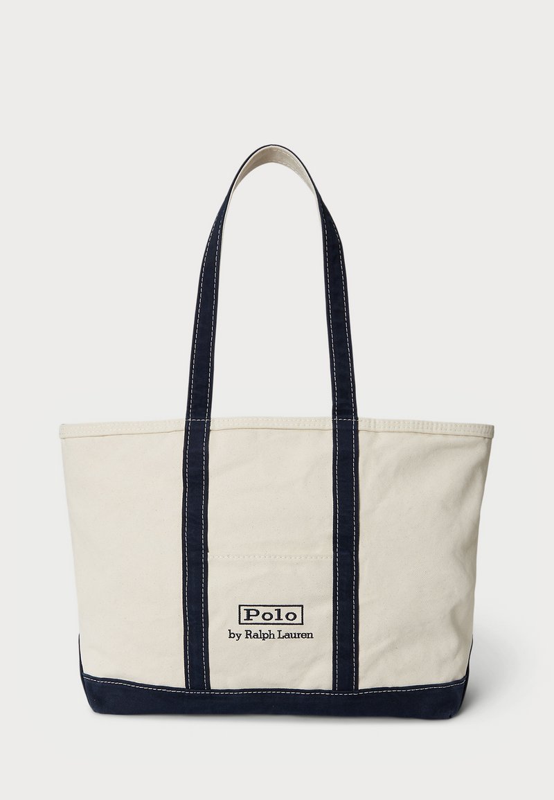 Krémszínű vászontáska tengerészkék díszítéssel, két füllel, eltérő varrással és elöl egy "Polo by Ralph Lauren" felirattal ellátott folttal.