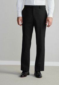 Pantalones de vestir negros con diseño de pierna recta, que presentan una parte delantera plana y trabillas para cinturón. El material parece suave y ligero. Combinados con zapatos negros.