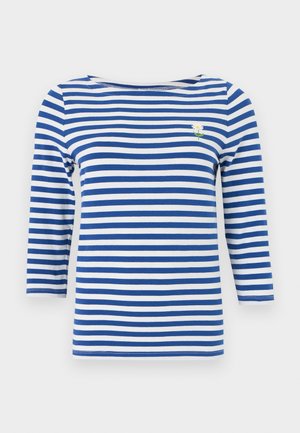 Kék-fehér vízszintes csíkos, hosszú ujjú ing, amelynek bal mellrészén egy kis hímzett fehér margaréta található.