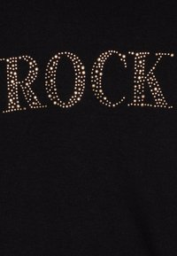 T-shirt preta com a palavra "ROCK" em strass brilhantes, com uma textura de tecido suave e um design ajustado.