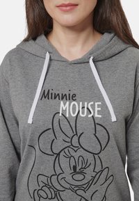 Felpa grigia con lacci bianchi; presenta una grafica con contorno nero di Minnie Mouse e il testo "Minnie" e "MOUSE" in colori a contrasto.