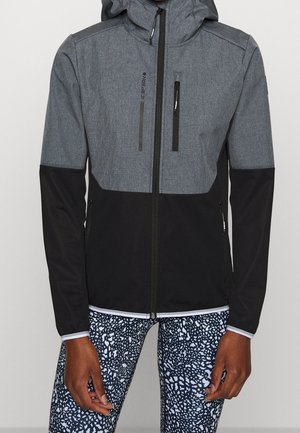 Graue und schwarze Kapuzenjacke mit vorderem Reißverschluss sowie Reißverschlusstaschen an Brust und Seiten, getragen mit schwarz-weiß gemusterten Leggings.