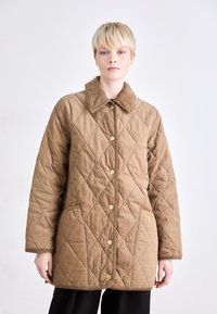 Gepolsterte braune Jacke mit einem Baumwollkragen, goldenen Knöpfen und zwei Fronttaschen. Hat ein Rauten-Muster und einen geraden Schnitt.