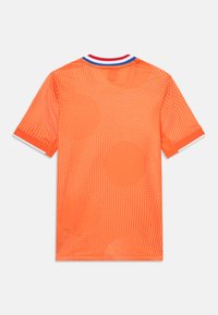 Kortsleeve oransje skjorte med teksturert mønster av hvite prikker og større sirkler, med en blå og rød ribbet rund hals.