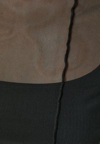 Tissu en maille dans des nuances de marron et de noir, avec un motif texturé et un détail en cordon noir tressé le long de la couture.