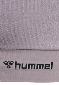 Paarse stof met een textuurpatroon, voorzien van een contrasterend zwart "hummel"-logo en bijenicoon op een dikkere ribbelband.