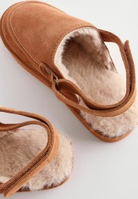 Suede brune hjemmesko med justerbare stropper, fluffy cremeforing, blød tekstureret sål og en gummiydersål for godt greb.