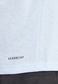 Svetlomodré tričko s jemnou textúrou, s malým čiernym logom "AEROREADY" blízko lemu. Štandardný strih s krátkymi rukávmi.