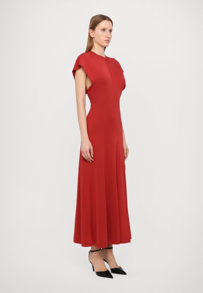 Punainen maxi-mekko virtaavalla muotoilulla, jossa on lyhyet hihattomat hihat, korkeakauluksinen design ja sileä pinta. Yhdistetty mustiin kärkitossuihin.