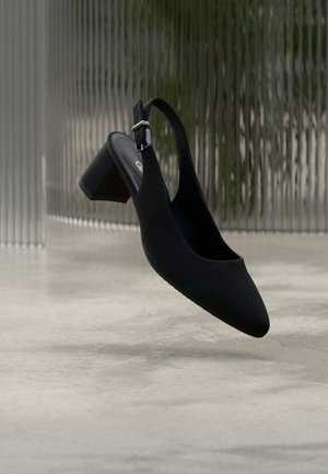 Black, pointed-toe slingback shoe with a mid-height block heel, smooth texture, adjustable ankle strap, and minimalistic design.