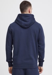 Sudadera con capucha de color azul marino, fabricada en un tejido suave, con un corte relajado, mangas largas y puños y dobladillo acanalados. Diseño simple y minimalista.