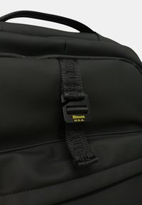 Zaino nero con superficie texturizzata, doppie maniglie superiori e una fibbia con marchio. Include un design elegante e materiale resistente.
