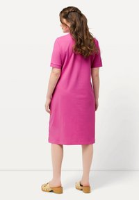 Abito di cotone rosa con maniche corte, design a lunghezza ginocchio, spacchi laterali e vestibilità comoda, abbinato a sandali con plateau in legno.