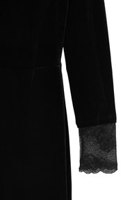 Manica di un abito in velluto nero con un merletto decorativo al polsino. Tessuto liscio con una leggera lucentezza e design classico.