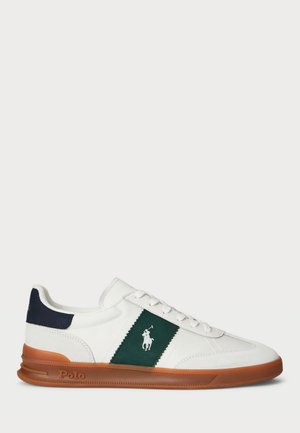 Witte sneakers van canvas. Beschikt over een groene stoffen streep en een marineblauwe accent op de hiel. Rubberzool met een bruine afwerking. Logo aan de zijkant.