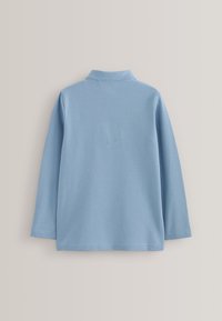 Polo bleu clair à manches longues avec un col doux, vu de dos sur un fond neutre uni.