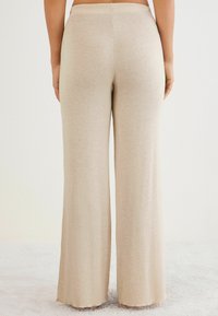 Wijde broekspijpen in een lichtbeige kleur, gemaakt van zacht, textuurstof. Heeft een gladde tailleband en afgewerkte randen, geschikt voor casual gebruik.