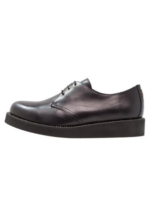 Chaussures en cuir noir à lacets avec un bout rond, présentant une texture lisse et une semelle en caoutchouc noir épais. Design minimaliste avec des accents subtils.