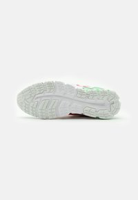 Vit gummisula för löparskor med strukturerade mönster, med inslag av röd och grön. Robust, designad för grepp och prestanda.