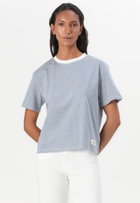 Tricou striped în bleu marin și alb, cu mâneci scurte, gât în formă de cerc, ajustat ușor boxy, cu un mic etichete de marcă în partea stângă jos.
