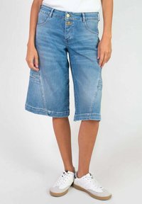 Culottes en denim bleu avec deux poches avant, deux poches arrière et une fermeture à bouton. Le tissu a une texture lisse et des zones effacées.