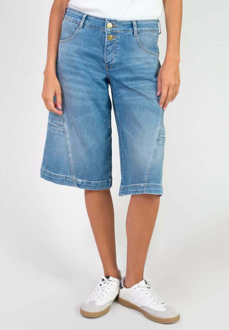 Culottes en denim bleu avec deux poches avant, deux poches arrière et une fermeture à bouton. Le tissu a une texture lisse et des zones effacées.