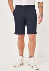 Marineblaue Shorts aus strukturiertem Stoff mit Vordertaschen, einem einzelnen Knopfverschluss und geradem Schnitt, der oberhalb des Knies endet.