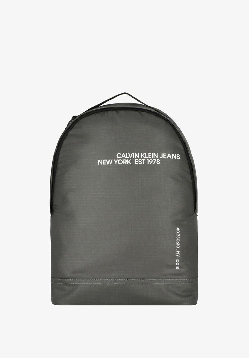 Zaino grigio realizzato in tessuto resistente con una finitura strutturata. Presenta testo del logo bianco e dettagli numerici nell'angolo inferiore.