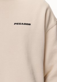 Pegador LOGO OVERSIZED  - Jersey con capucha - washed desert sand/black gum