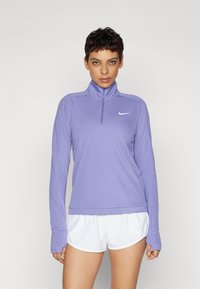 Svijetloplavi dukserica dugih rukava na zip, s visokim ovratnikom, sa malim bijelim Nike logotipom na prsima i dugim rukavima s otvorima za prste.