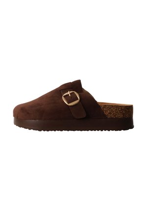 Sabot marron en daim avec une bride à boucle dorée et une semelle en liège, avec une semelle en caoutchouc marron foncé.