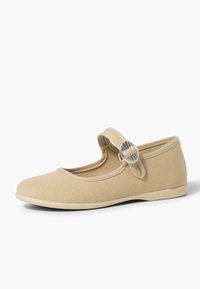 Beige Canvas Mary Jane-Schuhe mit runder Zehe, verstellbarem Riemen und kreisförmiger silberner Schnalle. Flache Gummisohle mit gestickten Details.