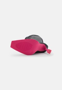 Chaussures noires avec une semelle en caoutchouc texturée; talon et semelle extérieure rose vif; languette pour un enfilage facile; design minimaliste.