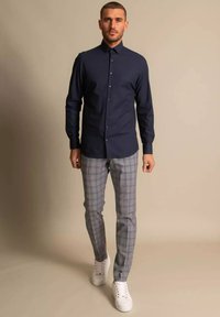 Marineblå skjorte med slim fit, kombinert med grå rutete bukser og hvite joggesko. Glatt stoff og skreddersydde designdetaljer.