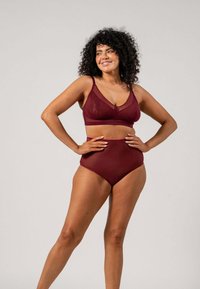 Burgundy bh med genomskinliga meshpaneler och justerbara axelband, matchad med högmidjad bikiniunderdel som visar upp en mjuk textur och modern design.