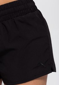 Svarta atletiska shorts gjorda av lättviktsmaterial, med ett elastiskt midjeband och en liten logotyp på den nedre sidan.