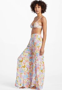 Virágmintás bikini szett pasztell színvilággal, háromszög alakú felsővel és széles, áramló nadrággal, amelyet színes virágminta díszít.