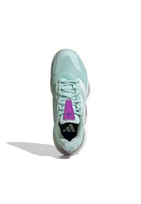 Zapatilla deportiva de color verde claro con parte superior de malla, acentos blancos y lengüeta morada. Cuenta con cordones y suela acolchada para mayor comodidad.