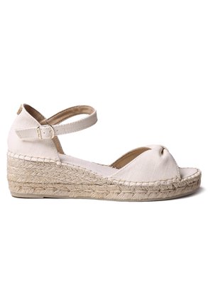 White canvas espadrille wedge sandal with a rounded toe, peep-toe design, ankle strap, and braided jute sole.