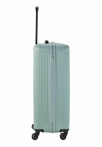Valise rigide en vert pastel avec une texture à stries verticales, poignée rétractable et quatre roues noires pour la mobilité.